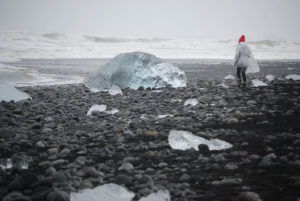Rocky beach with scattered ice chunks and waves in the background, photographed at Diamond Beach, Iceland.