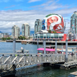Waterfront view of Vancouver, British Columbia, featuring Science World’s geodesic dome, modern skyline, small boats, and mountains under a bright blue sky in a host city for the FIFA World Cup 2026.